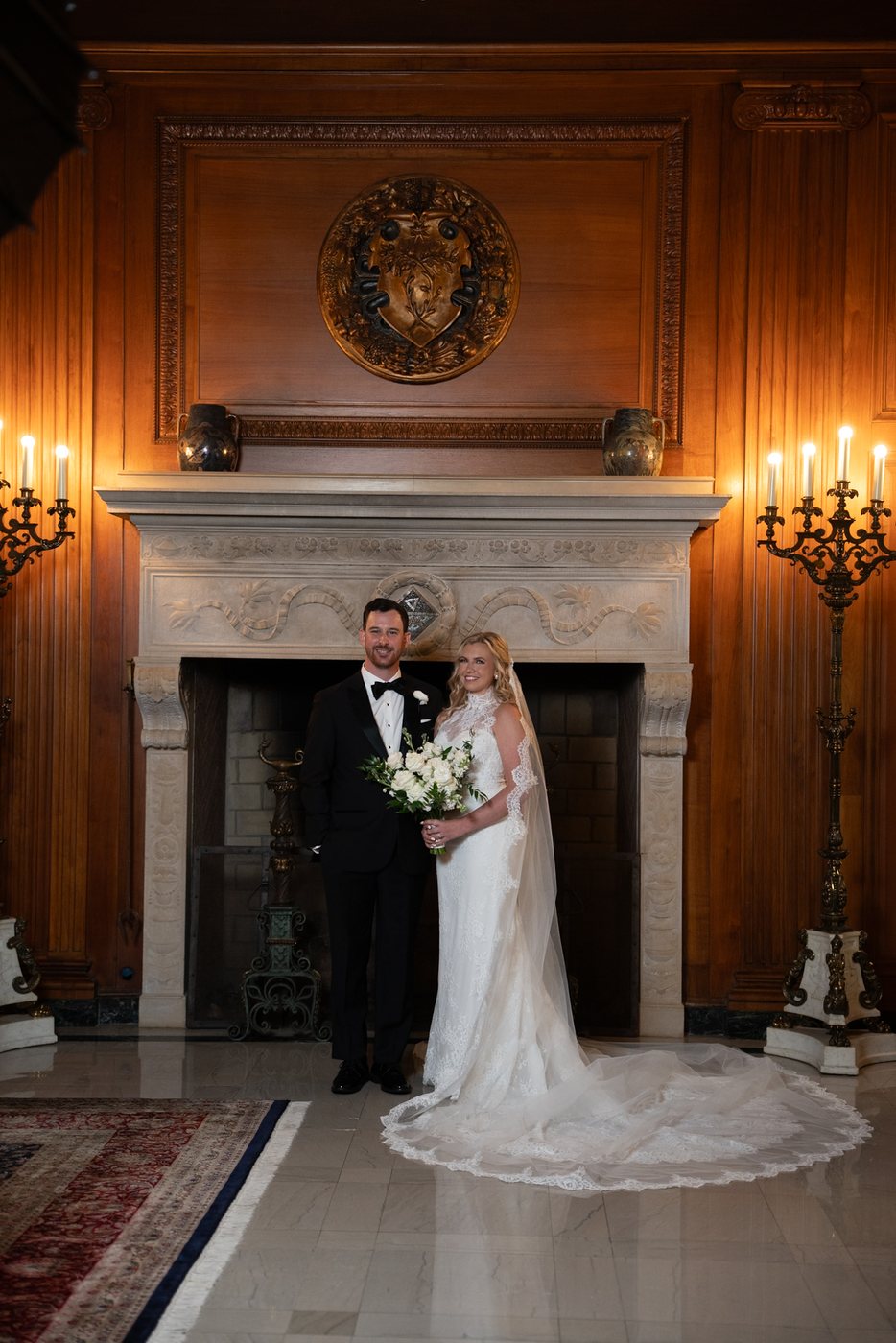 Couple beside a fireplace in a warmly lit room, before editing; photograph by Michele Maloney
