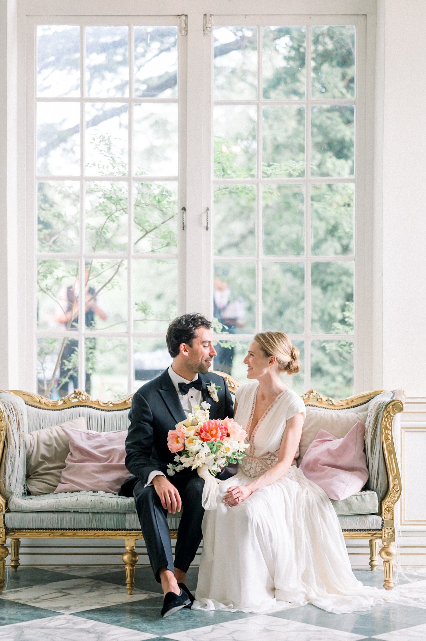 Newlyweds seated beside a conservatory window, after editing