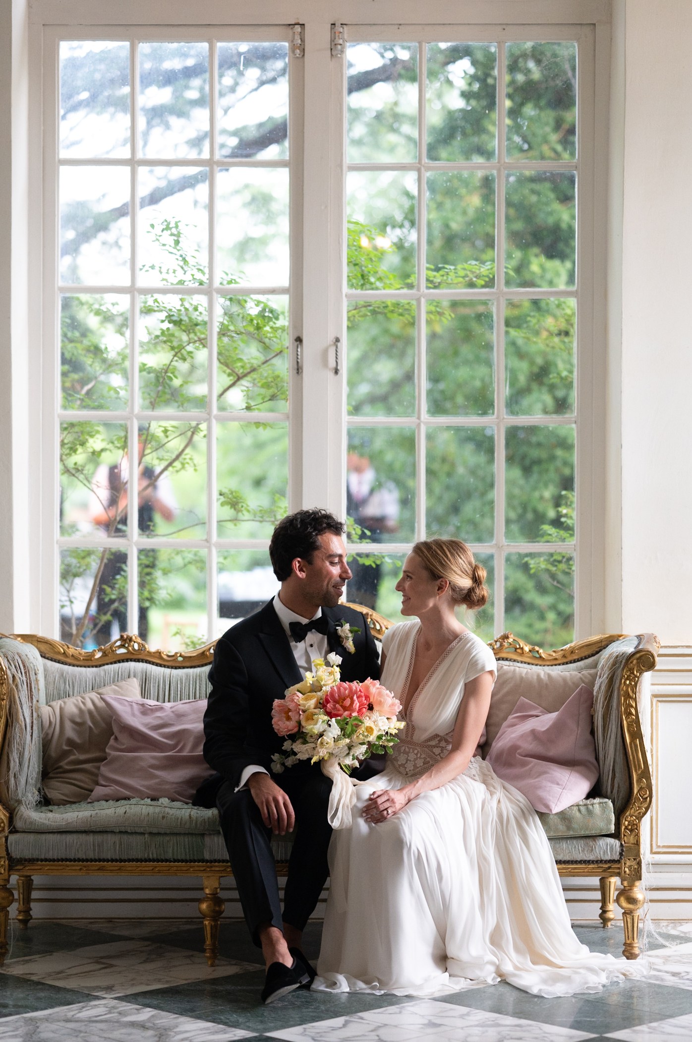Newlyweds seated beside a conservatory window, before editing