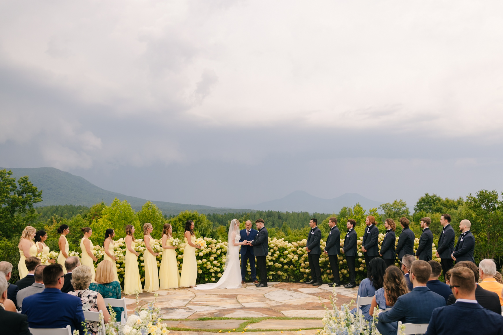 Outdoor wedding ceremony with mountain views and a bridal party in pastel yellow