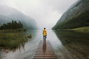 young adult male wearing yellow jacket standing on a footbridge