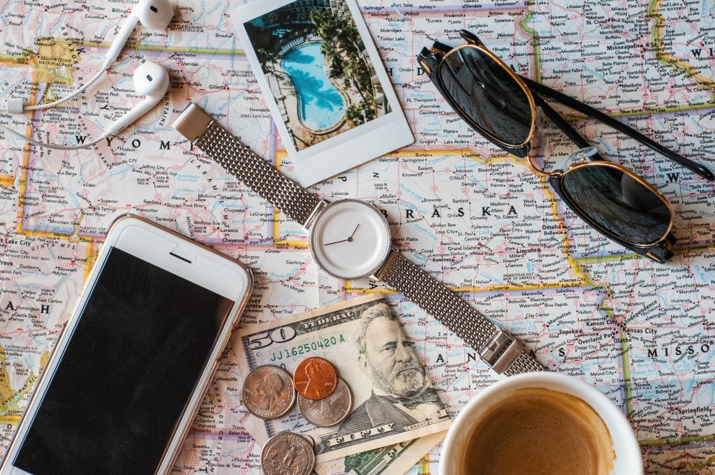 close up of smartphone, watch, sunglasses, money, coffee on the