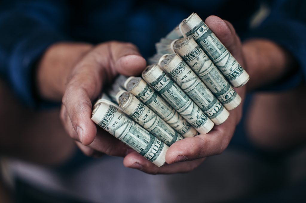 man's hands holding many bundles of cash