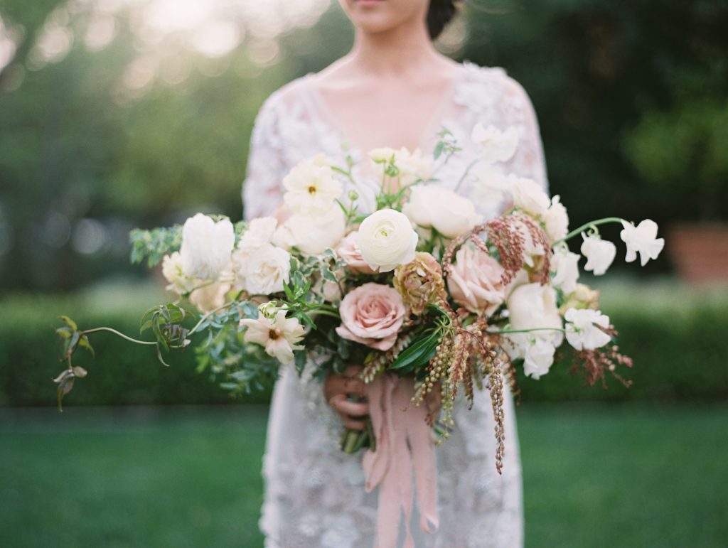 mid section of a bride holding a flower bouquet