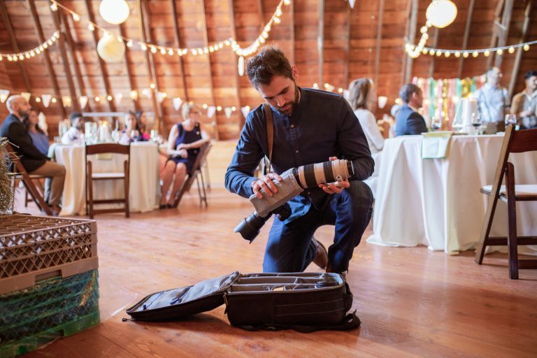 male photographer preparing camera equipment at wedding receptio