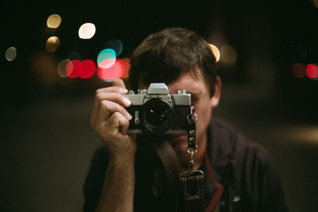 photographer posing with a film camera
