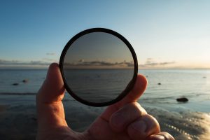 man holding gradient neutral density nd filter on background of summer sunset