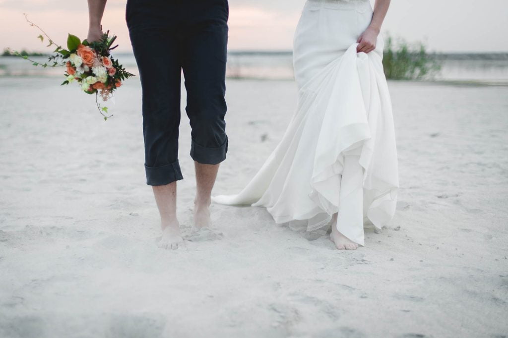 bride and groom walk on the beach