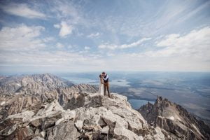 newlywed couple kisses on summit of beautiful stunning rocky mou